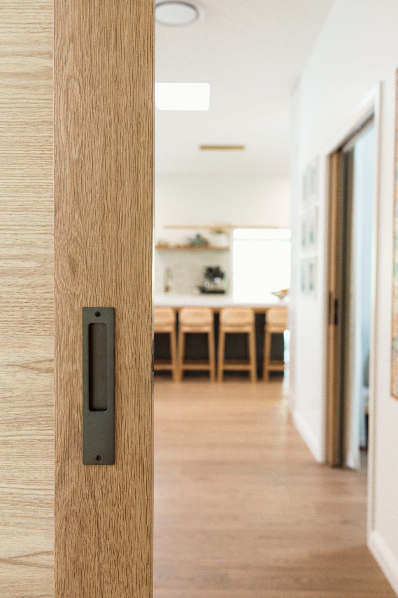 A timber door features the Rectangular Sliding Door Pull in Signature Brass.